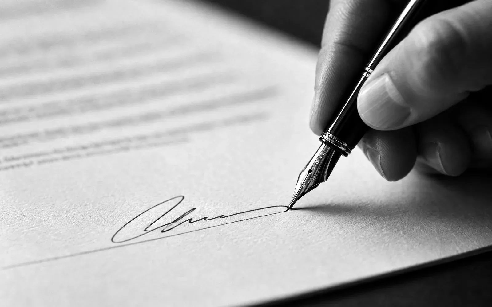 A hand signing a document with a fountain pen